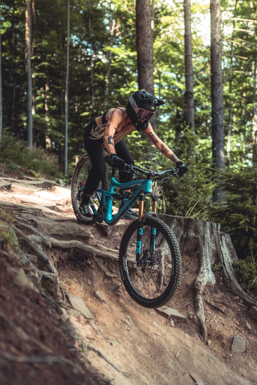 a girl on a blue mountain bike going throught a forest